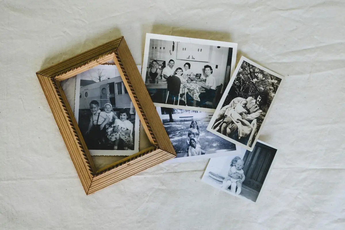 Old family photographs and a wooden frame laid on a white sheet