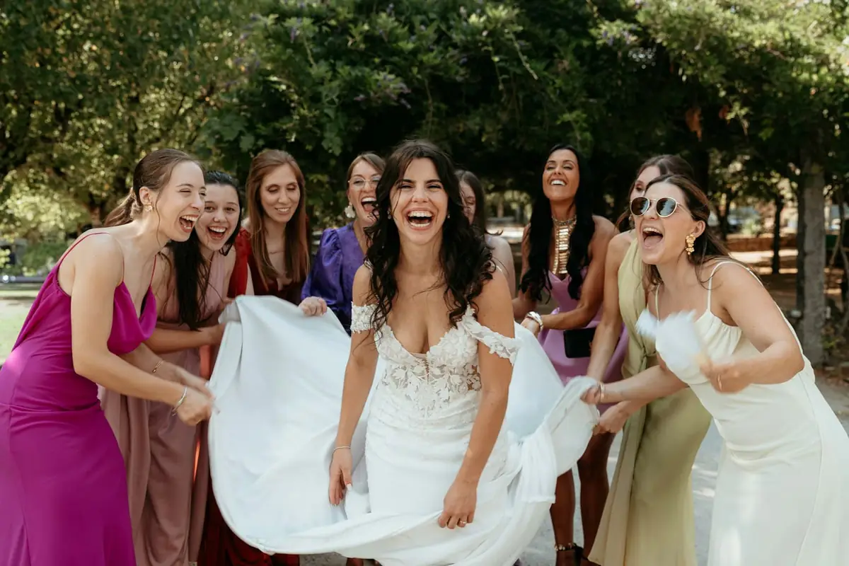 A bride laughing with her bridesmaids outdoors