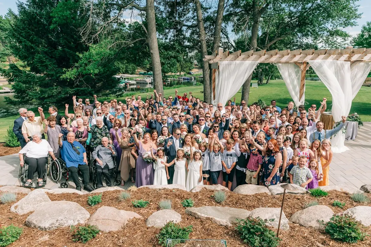 A large group of wedding guests posing together outdoors