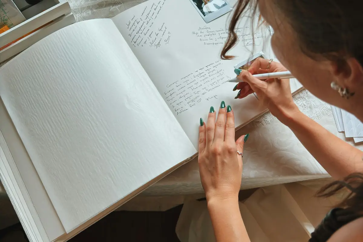 A guest writing a message in a wedding guest book